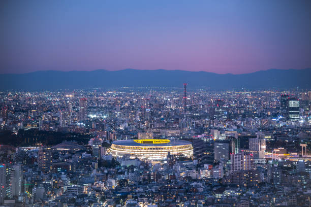 Aerial view of Olympic Stadium in twilight TOKYO, JAPAN - November 30, 2019 : Overhead aerial view of the new National Stadium with Tokyo's skyline in twilight time, fully completed main stadium for Tokyo Olympic Summer Games 2020 olympic city stock pictures, royalty-free photos & images