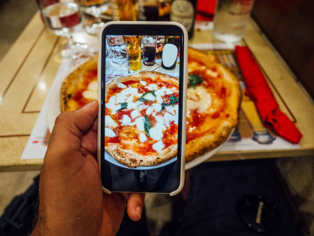 мужчина фотографит свою пиццу в ресторане в неаполе, италия - margharita pizza фотографии стоковые фото и изображения