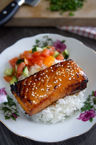 A fillet of salmon teriyaki served with white rice and vegetables.
