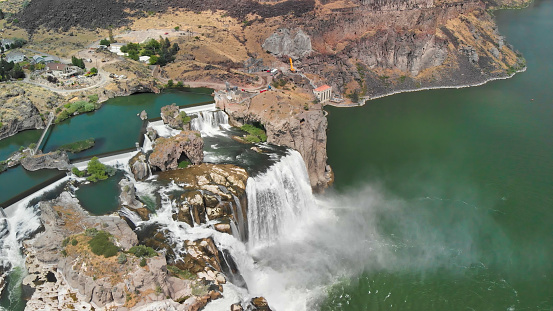 After the storms is a view of the strong gushing water outflow from the Morris Dam drain complex with two pickup trucks, workers, and concrete dam wall for the background.