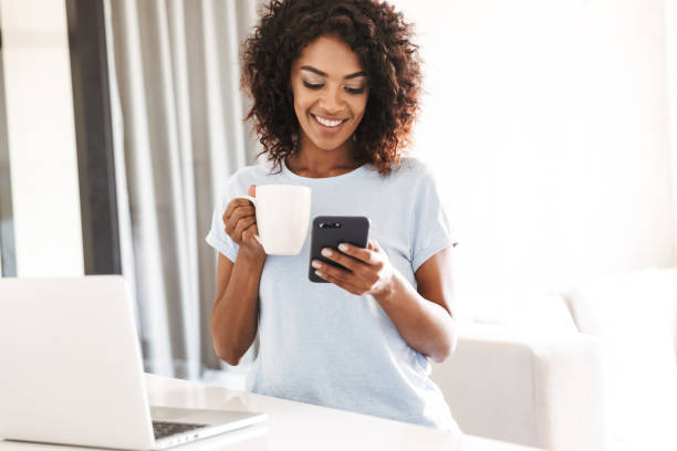 istock Smiling african woman using mobile phone 1327491716