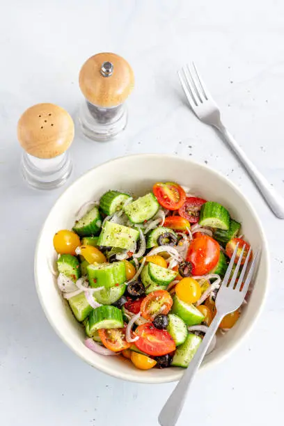 Healthy Cucumber and Tomato Salad in a Bowl on White Background