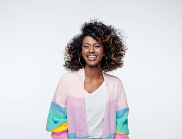 Excited woman wearing rainbow cardigan Cheerful african young woman wearing rainbow cardigan laughing at camera. Studio portrait on white background. afro hairstyle photos stock pictures, royalty-free photos & images