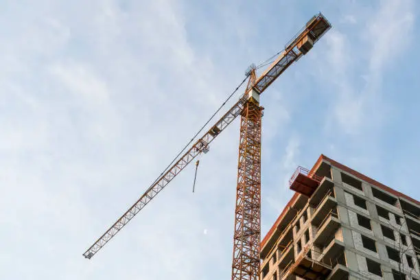 Building construction site and tower crane against blue sky. Growth concept. Copy space for text.