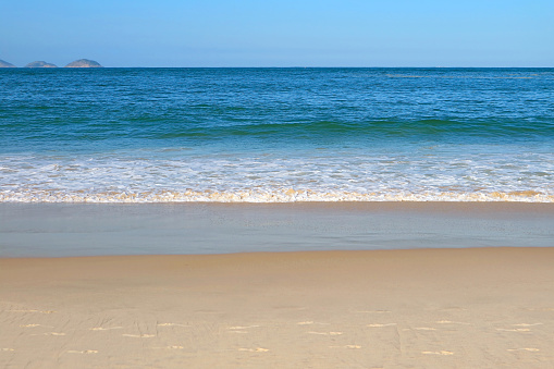 Gentle waves of the vivid blue sea splashing the empty beach