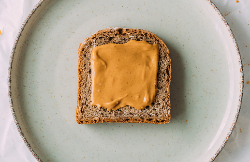 A slice of rye bread with peanut butter spread on it