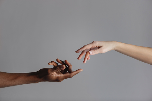 Male and female hands reaching out to each other isolated on grey background. Human relations concept.