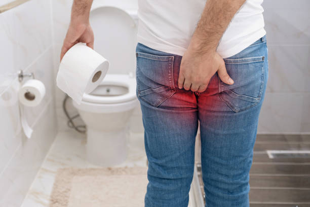 Man suffering from hemorrhoids pain holding toilet paper roll in toilet. Man suffering from hemorrhoids pain holding toilet paper roll in toilet. constipation stock pictures, royalty-free photos & images