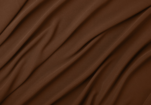 Close up abstract textile background of dark brown folded pleats of fabric, elevated top view, directly above