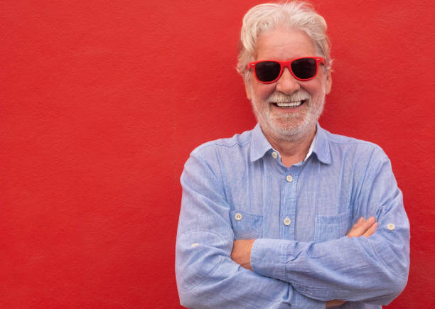 istock Cheerful man with crossed arms standing on red background, smiling happily looking at camera, caucasian senior people with white beard and hair 1327519097