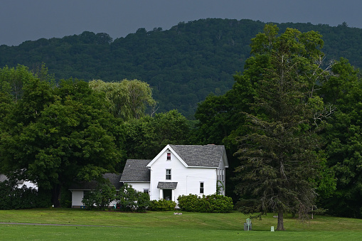 A coming thunderstorm over Mount Rat in Washington, Connecticut, with a white farmhouse in the foreground