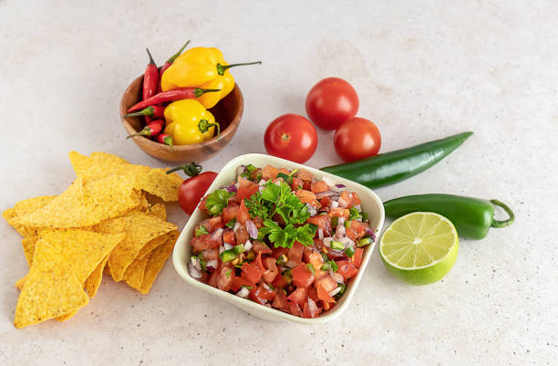 istock Mexican appetizer Pico de Gallo in a bowl and ingredients on the table. 1327520411