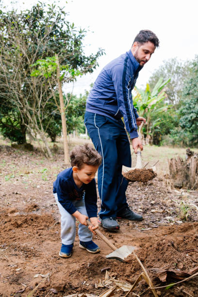 istock Father and son digging a hole to plant a tree 1327521331
