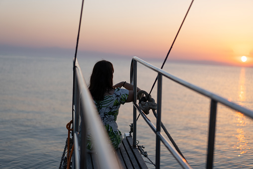 woman sitting on the sailboat during sunset