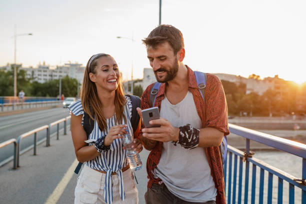 istock A young couple of tourists using mobile phone and walking 1327522575