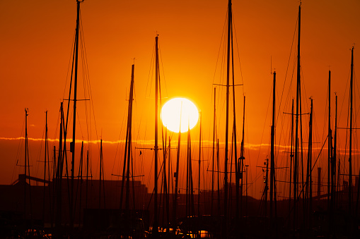 Gorgeous red sunset over marina with sailboat masts in silhouette.