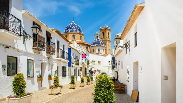 Street of Altea old town in Spain. Beautiful village with white houses and blue domed church Our Lady of Solace. Popular Spanish tourist destination in Costa Blanca region