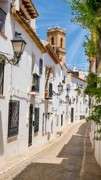 Typical street of Altea old town with white houses in Spain. Beautiful village with cobblestoned narrow streets, popular tourist destination in Costa Blanca region. Vertical orientation