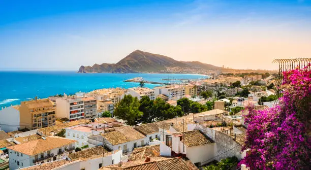 Altea, Spain - beautiful village with white houses, pink bougainvillea flowers, beach, harbour and mountains at sunset. Popular Spanish tourist destination in Costa Blanca region on Mediterranean sea