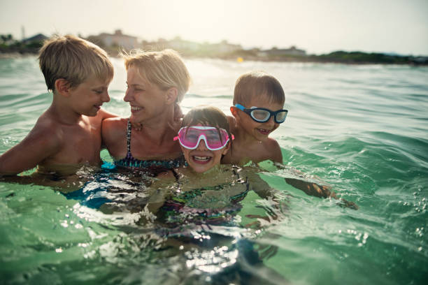 istock Mother with three kids splashing in sea waves 1327525811