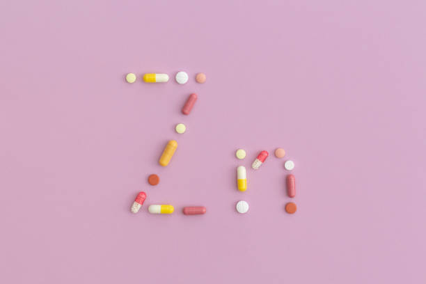 zink-symbol aus pillen auf lila hintergrund. top-ansicht mit kopierbereich. flach liegen. - capsule vitamin pill letter k medicine stock-fotos und bilder