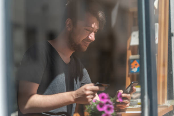 istock Young man holding credit card, using smartphone for online shopping 1327526515
