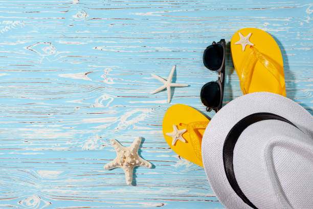 istock yellow rubber flip flops, white beach hat, starfish on a blue wooden background 1327527819