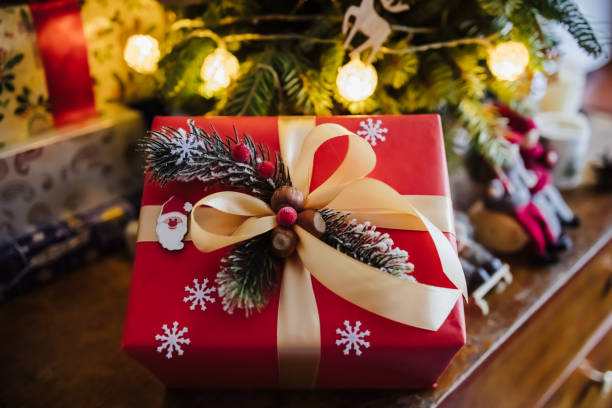 istock beautifully wrapped red gift box under the christmas tree, top view 1327528755