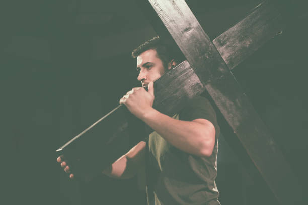 Young man carrying a wooden cross. stock photo