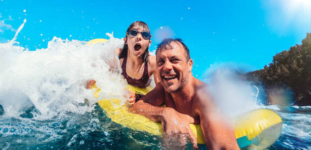 istock Father and daughter having fun on the beach while floating on airbed 1327532538