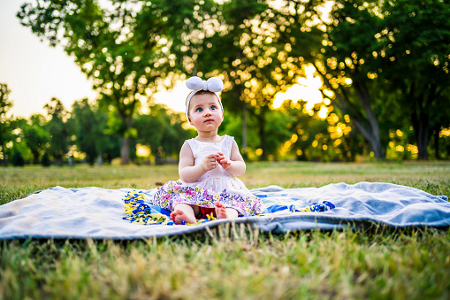 Adorable cute baby girl sitting on green meadow