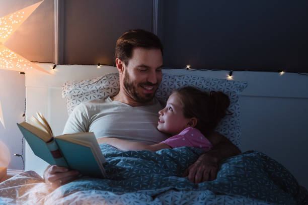 istock Father reading a book for his daughter at night time 1327536861