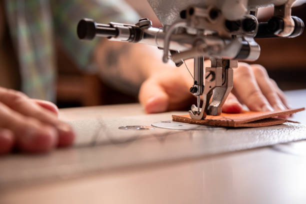 istock Close up craftsman hands sew stuff blank for wallet use sewing machine. Working at leather workshop 1327537658
