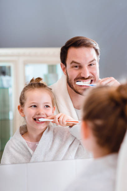 istock Father and daughter brushing teeth 1327538080
