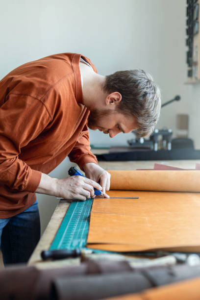 istock Male tanner making cutting scheme of bag working at leather workshop. Handcrafted creating 1327539013