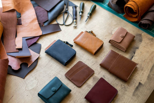 istock Craftsman hands laying out leatherwork on wooden table at leather workshop. Handwork accessories 1327540453