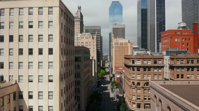 Forwards reveal of buildings along downtown street. Fly between various buildings. Dallas, Texas, US