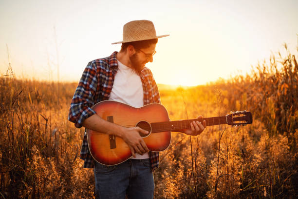 istock Handsome man playing guitar outdoors during the sunset 1327551419