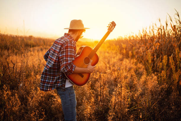 istock Handsome man with guitar walking on the field 1327551421