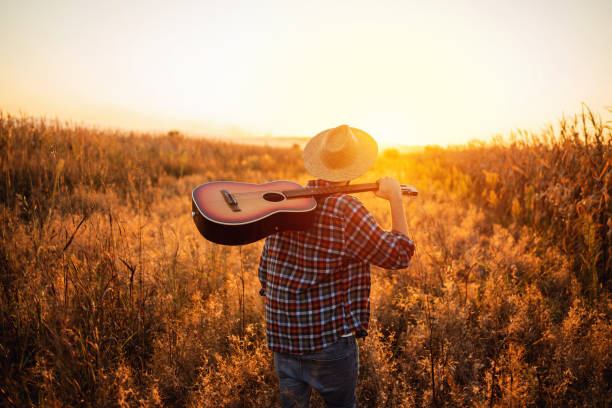 istock Unrecognizable man with guitar walking on the field 1327551423