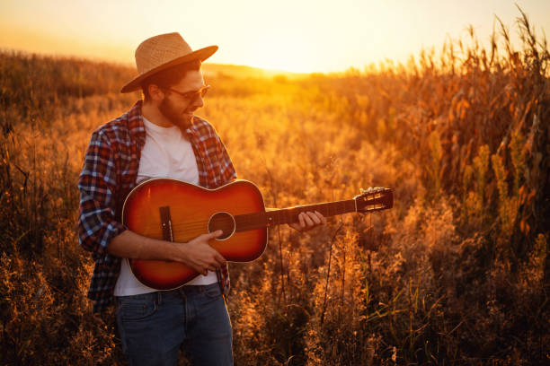 istock Smiling handsome man playing guitar outdoors during the sunset 1327551425