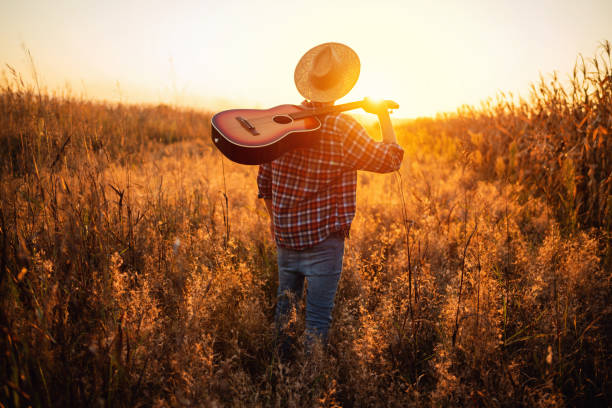 istock One unrecognizable man with guitar walking on the field 1327551427