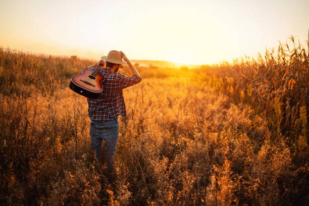 istock One unrecognizable Caucasian man with guitar walking on the field 1327551430