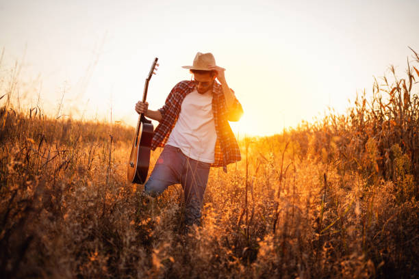 istock One handsome man with guitar walking on the field 1327551437