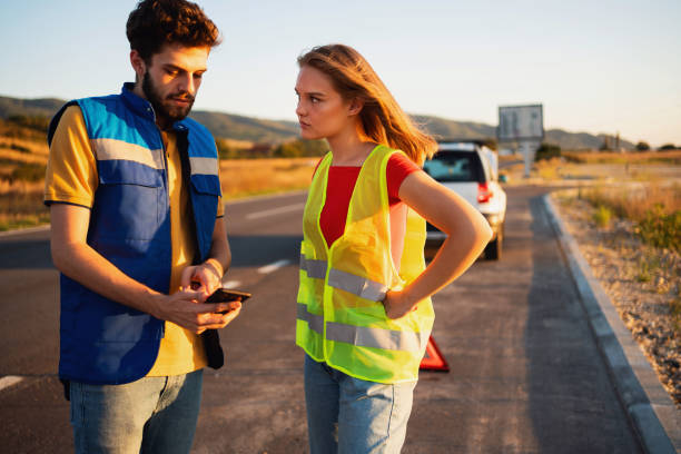 istock Service worker consulting with young woman about problem with her broken car on the road 1327552177