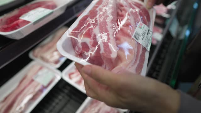 super market shopper hands picks up packaged fresh pork belly