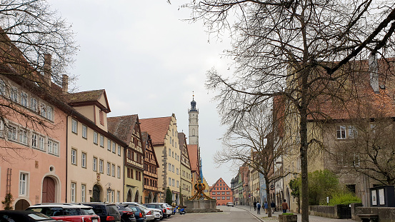 Rothenburg ob der Tauber, Bavaria in Germany - April 9, 2019: People walking and parked cars in the morning on the street of the famous historic town, Rothenburg ob der Tauber