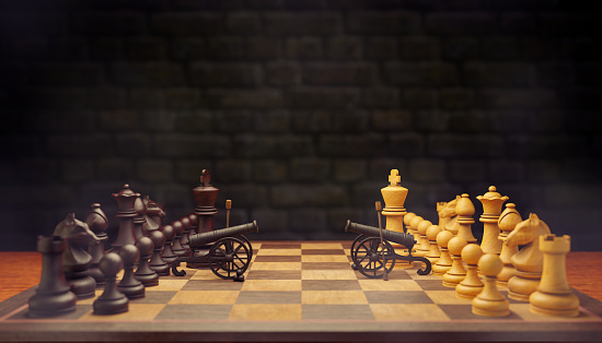 The two chess pieces are going to war. They both use cannons as their weapons on a chessboard with a brick wall background. The concept of business warfare using business strategy. 3D illustration.