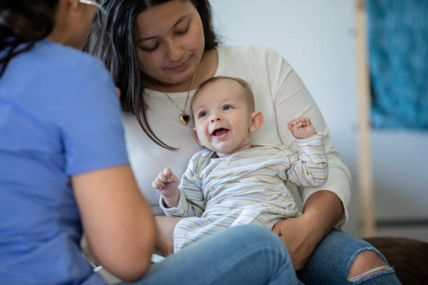 baby smiles while being examined by a nurse or doctor during a house call medical exam - visita imagens e fotografias de stock