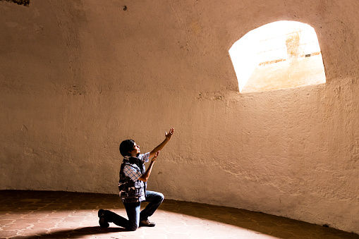 man with arms raised towards a window light , inspiration concept